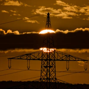 Sonnenaufgang hinter Wolken und einem Strommast.